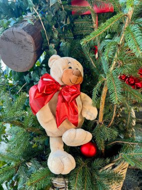 Noel ağacının dallarında kırmızı kurdeleli oyuncak ayı. Yeni Yers ve Noel konsepti.