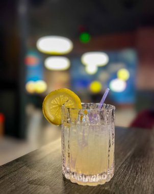 Arkaplanı bulanık, ahşap bir masada limonlu ve buzlu alkol kokteyli.