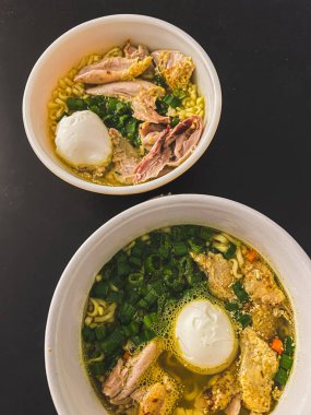 Chicken noodle soup with egg in bowl, green onion and meat in Asian food style. Top view