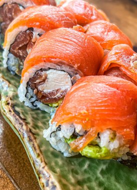 Somon suşisi Japon usulü soya soslu siyah kovada yuvarlanıyor. seçili odak noktası
