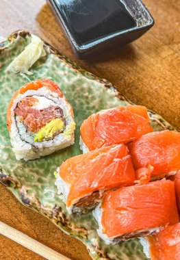 Somon suşisi Japon usulü soya soslu siyah kovada yuvarlanıyor. seçili odak noktası
