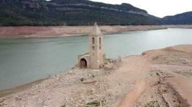 Sahilde terk edilmiş bir kilisenin olduğu kuru su deposu. Katalonya, İspanya 'daki kurumuş rezervuar Sau. Kuraklık. İklim değişikliği kuraklık kara ve su rezervuarında, insansız hava aracı görünümü