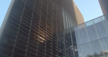 Akşamları ofis binasının önünde güneşin yansıması. Akşamları uzun bir iş merkezinin panoramik manzarası. Güneşli bir günde gökdelen cam cepheleri