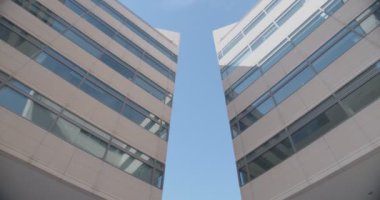 Mavi gökyüzü ve uçağın arka planına karşı bir ofis binasının güzel alt manzarası. Hafif beton ve camdan yapılmış bir ofis binası cephesi