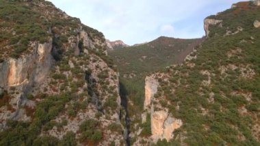 İki yüksek uçurum arasındaki uçuş. İHA yüksek bir uçurum boyunca uçar, güneşli havada dağ sırasının panoramik görüntüsü, 4k