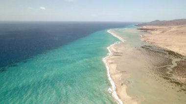 Beyaz temiz kum ve kristal berrak suyla sahilin muhteşem insansız hava aracı görüntüsü. Turkuaz zümrüt renkli suyla beyaz kumsalda dalgalanan temiz okyanus dalgaları