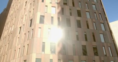 Gün batımı ofis binasının cam cephesine yansıyor. İş, finans ve başarı konularında motive edici bir video için klip