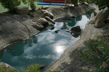 Küçük bir su akıntısı kayalık bir alandan geçer. Su berrak ve sakin ve etrafını saran kayalar barışçıl bir atmosfer yaratıyor.