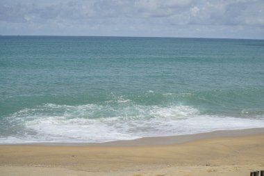 Okyanus sakin ve gökyüzü bulutlu. Kumsal boş ve su da mavinin güzel bir tonu.