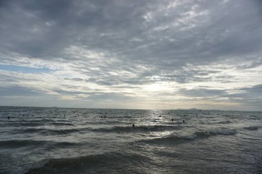 Okyanus sakin ve gökyüzü bulutlu. Su koyu mavi bir renktir. Gökyüzü kapalı ve güneş görünmüyor.