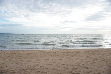 Sahil sakin bir okyanus ve bulutlu bir gökyüzü. Gökyüzü bulutlu ve su sakin.