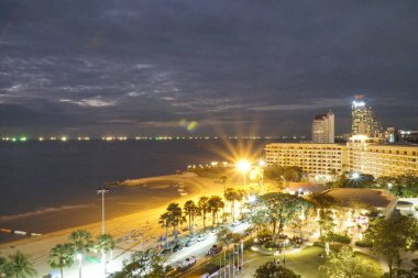 Geceleri plajda arka planda şehir silueti var. Şehirden ve plajdan gelen ışıklar sıcak ve davetkar bir atmosfer yaratır.