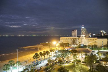 Sahilde geceleri arka planda bir şehir. Şehir aydınlandı ve sahil de aydınlandı.