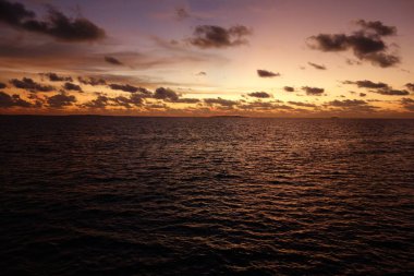 Güneş batarken gökyüzü güzel turuncu bir renktir. Su sakin ve durgun, gökyüzünün renklerini yansıtıyor.