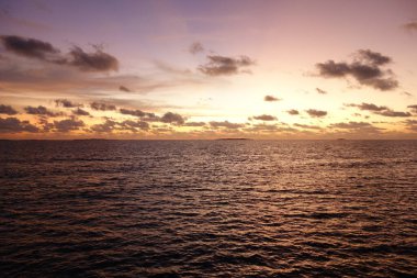 Gökyüzü turuncu ve pembe renklerin güzel bir karışımıdır. Huzurlu ve huzurlu bir atmosfer yaratır. Okyanus sakin ve durgun, gökyüzünün renklerini yansıtıyor. Huzur ve rahatlama kavramı