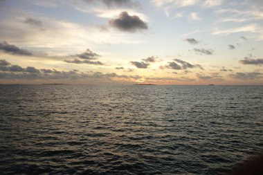 Güneş okyanusun üzerinde batarken gökyüzü turuncu ve pembe renklerin güzel bir karışımıdır.