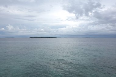 Okyanus sakin ve gökyüzü bulutlu. Su mavi ve gökyüzü gri.