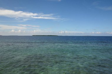 Okyanus sakin ve mavidir. Uzakta görünür bir kara parçası yoktur. Gökyüzü açık ve mavi, görünürde bulut yok. Huzurlu ve huzurlu bir sahne.