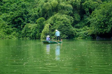 İşçiler, Ninh Binh, Vietnam 'daki Trang An turizm kompleksindeki nehri temizlemek için çöp topluyorlar..