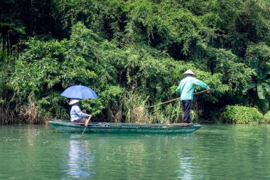 İşçiler, Ninh Binh, Vietnam 'daki Trang An turizm kompleksindeki nehri temizlemek için çöp topluyorlar..