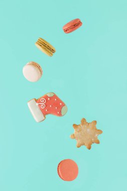 2023. Yeni yıl partisi dekoratif gıda konsepti renkli badem kurabiyeleri ve pastel turkuaz mavi arka planda yüzen zencefilli kurabiyelerle yapıldı. Asgari soyut Noel dekorasyonu fikri.