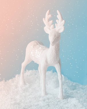 Minimum soyut Xmas büyülü sahnesi, karlı arka planda beyaz ren geyiği. İzole edilmiş pastel parlak mercan pembe-mavi gökyüzü. Yılbaşı gecesi dekorasyon konsepti. Noel sembolü ya da hediye kartı.