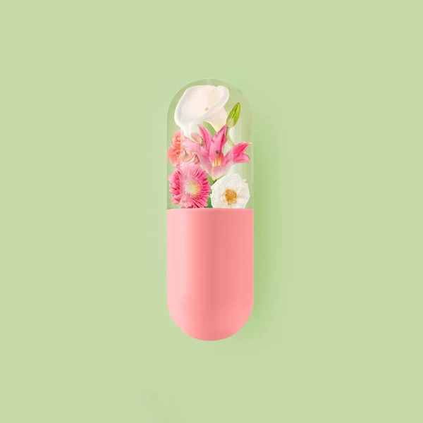 Rosafarbene Pille Mit Blühenden Bunten Blumen Auf Isoliertem Pastellgrünem Hintergrund Stockfoto