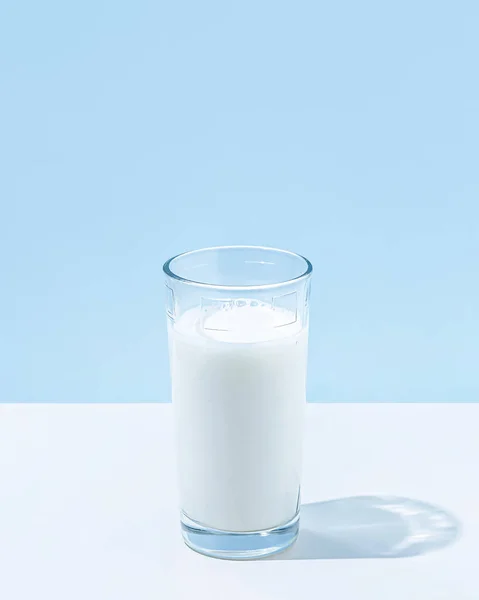 パステルブルーの背景にミルクのガラスと食べ物や飲み物の最小限の夏の概念 影と太陽の反射 健康飲料だ カルシウム タンパク質 ビタミンB2 B12 カリウムの乳製品ソース — ストック写真