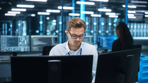 stock image IT Specialist Works on Two Personal Computer at the Software Program with Coding Language Interface. In the Background Technical Room of Data Center with Professional Working