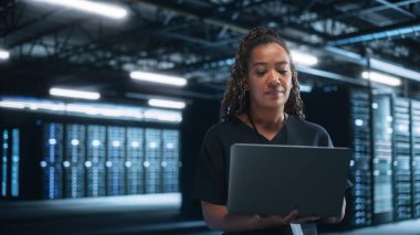 Ofis: Şık Giyimli Başarılı İş Kadını Dizüstü bilgisayarda çalışıyor ve Ekrana Bakıyor. En İyi Sonuçlara Ulaşmak İçin Geç Saatlere Kadar Çalışan Bayan Yönetici