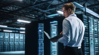 Veri Merkezi Erkek Uzmanı Bilgisayar üzerinde çalışırken dizüstü bilgisayar kullanıyor. Bilgi Teknolojisi Profesyoneli. Sunucu Çiftliği Bulutu Hesaplama ve Siber Güvenlik Bakım Konsepti