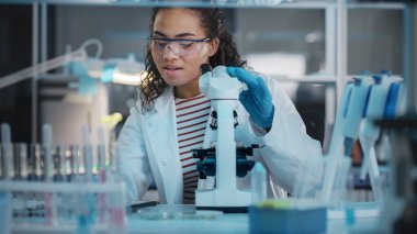 Tıbbi Bilimler Laboratuvarı: Mikroskop kullanarak Güzel Siyah Bilim Adamı Portresi Test Örnekleri Analizi Yapıyor. Hırslı Genç Biyoteknoloji Uzmanı, Gelişmiş Ekipmanlarla çalışıyor.