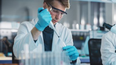 Modern Tıp Laboratuvarı: Genç Kafkas Erkek Araştırma Bilimadamı Test Tüpündeki Mikro Pipette kullanarak Kimyasal Sıvıları Karıştırıyor. Mikrobiyologlar biyoteknoloji araştırması yapıyor. Portre Çekimi