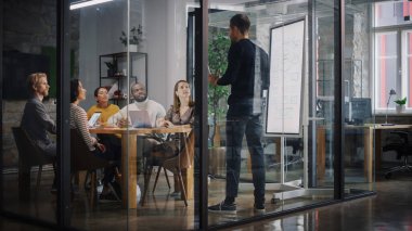 Proje Müdürü Ajans 'taki Toplantı Odası' nda Genç Yaratıcı Ekip için Sunum Yapıyor. Meslektaşlar Konferans Masasının Arkasında Oturur İş Geliştirme, Kullanıcı Arayüzü ve Tasarım.