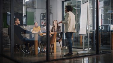 Proje Müdürü Ajans 'taki Toplantı Odası' nda Genç Yaratıcı Ekip için Sunum Yapıyor. Meslektaşlar Konferans Masasının Arkasında Oturur İş Geliştirme, Kullanıcı Arayüzü ve Tasarım.