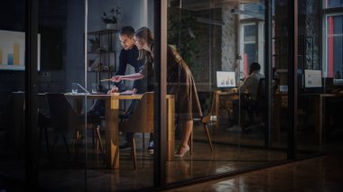 İki Genç ve Başarılı İş Arkadaşı Bir Teşkilatta Cam Duvarların Arkasında Toplantı Odasında Sohbet Ediyor. Güzel Kadın Yönetmen ve Yakışıklı Proje Yöneticisi Laptop Bilgisayarında Çalışmayı Tartışıyor.