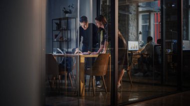 İki Genç ve Başarılı İş Arkadaşı Bir Teşkilatta Cam Duvarların Arkasında Toplantı Odasında Sohbet Ediyor. Güzel Kadın Yönetmen ve Yakışıklı Proje Yöneticisi Laptop Bilgisayarında Çalışmayı Tartışıyor.