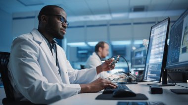 Modern Elektronik Geliştirme Tesisi: Kara Mühendis ve Çoklu Etnik Bilimciler Ekibi Bilgisayarlar Üzerinde Çalışıyor, CAD Yazılımı, Tasarım Endüstriyel PCB, Silikon Mikro Çipleri, Yarı iletkenler