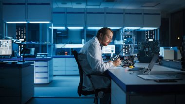 Modern Elektronik Araştırma ve Geliştirme Tesisi: Akıllı Kafkas Erkek Mühendis Bilgisayar Anakart Lehim Yapıyor. Bilim adamları Endüstriyel PCB, Silikon Mikroçipler, Yarı iletkenler Tasarım