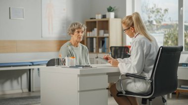 Kadın Aile Doktoru, bir Sağlık Kliniği 'nde danışmanlık sırasında yaşlı kadınların tıbbi sorunlarını yazıyor. Laboratuvar Önlüğü Hekimi, Hastanedeki Yaşlı Hastaya İlaç Yazıyor.