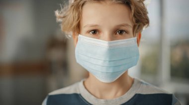 Kapalı alanda koruyucu maske takan yakışıklı bir gencin yakın portresi. Kahverengi Gözlü Sarışın Erkek Karantina Kurallarına Saygı duyuyor, Güvenlik önlemleri ve Güvenli Sosyal Mesafe. Salgın Konsepti.