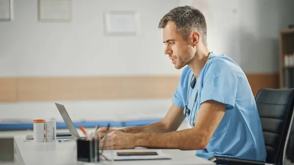 Ervaren Mannelijke Verpleegkundige Dragen Blauwe Uniform Werken Laptop Computer Bij — Stockfoto