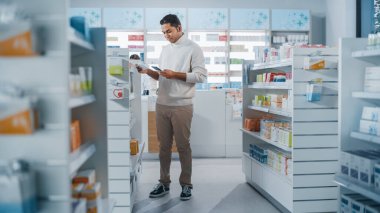 Eczane: Akıllı Telefon Kullanan Yakışıklı Hintli Adamın En İyi İlacı, Uyuşturucuyu, Vitamini Ararken Çekimi. Raflar dolusu sağlık, sağlık ve spor malzemeleri.