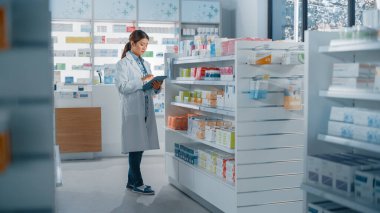 Eczane: Güzel Asyalı eczacı dijital tablet bilgisayar kullanıyor, ilaç, vitamin ve sağlık ürünleri envanterini kontrol ediyor. Eczacı dükkanında profesyonel eczacı.