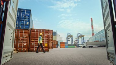 Sarışın Siyah Endüstriyel Mühendis Yelek ve Kasa Terminalinde Yürüyen Güvenlik Yeleği. Ustabaşı veya Denetmen Lojistiği İşletir.