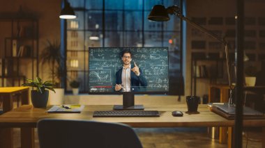 Matematik Formüllerini Açıklayan Sevimli Bir Erkek Öğretmenin Portresi ile Online Ders Veren Bir Masaüstü Bilgisayarının Çekimi. Modern Yaratıcılık Ofisi 'ndeki Ahşap Masa' nın üzerinde duruyor. Ilık Akşam Işığı