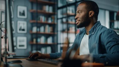 Yaratıcı Ev Oturma Odasında Masaüstü Bilgisayarı 'nda çalışan yakışıklı siyahi Amerikalı Uzman. Serbest Erkek Müşteriler ve İşverenler için Mali Sunum Raporu üzerinde çalışıyor.