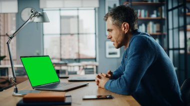 Ev Oturma Odası 'nda Yeşil Ekran Modeli ile birlikte laptopta görüntülü yakışıklı bir Kafkas Uzmanı sohbeti. Sosyal ağlarda Müşterilerle İnternet üzerinden Konuşan Serbest Adam.