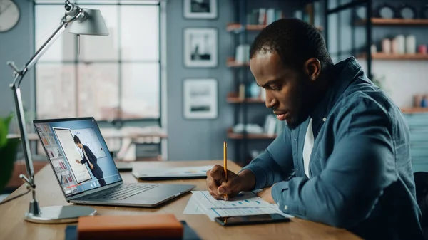 Oturma odasında masanın arkasında otururken bilgisayarında Afrikalı Amerikalı adamın online video dersi var. Serbest Çalışan Yetenekleri Üzerinde Çalışan Ya da İnternet Üzerinde Ödev Yapan Öğrenci.