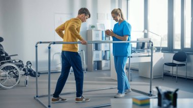 Hastane Fizyoterapi Odası: Paralel Barlar İçin Yürüyen Güçlü Hasta, Fizyoterapisti Yardımcıları Destekliyor, Engelli Kişinin Tedavi Etmesine Yardım Ediyor.